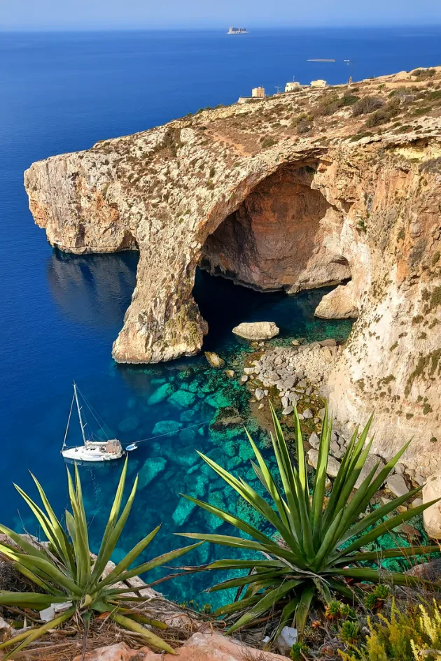 A small boat beside the sea arch at the Blue Grotto