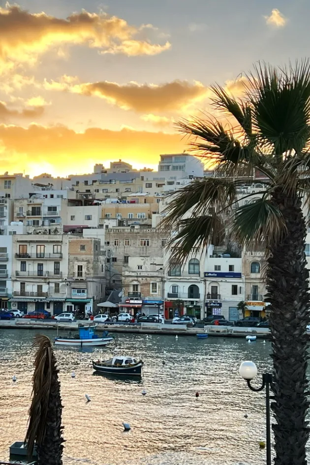 Sunset over the waterfront and moored boats at Marsaskala